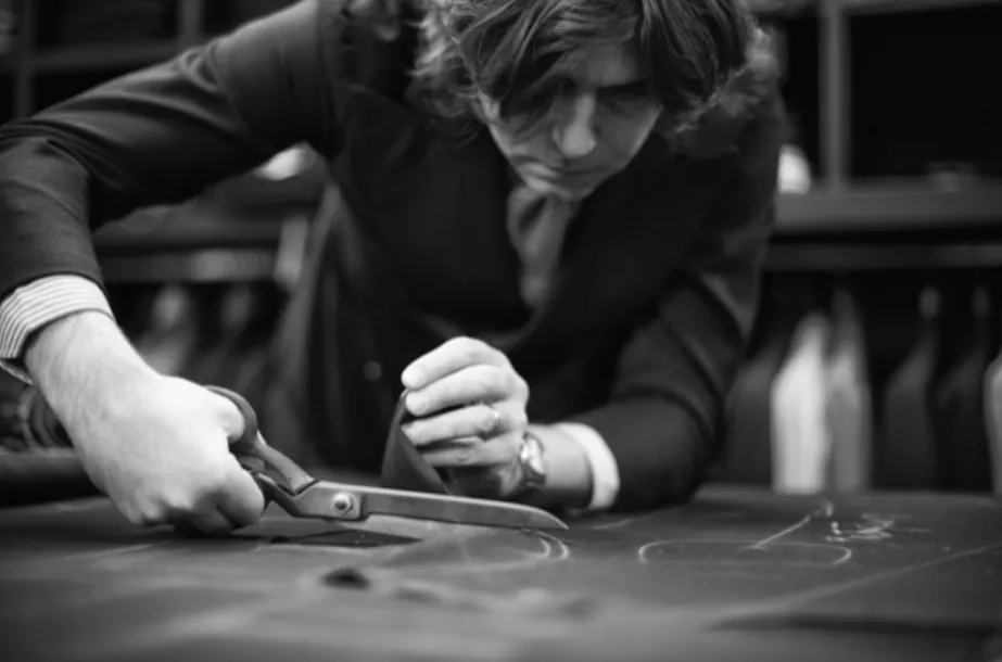 A Sciamat tailor cutting cloth by hand