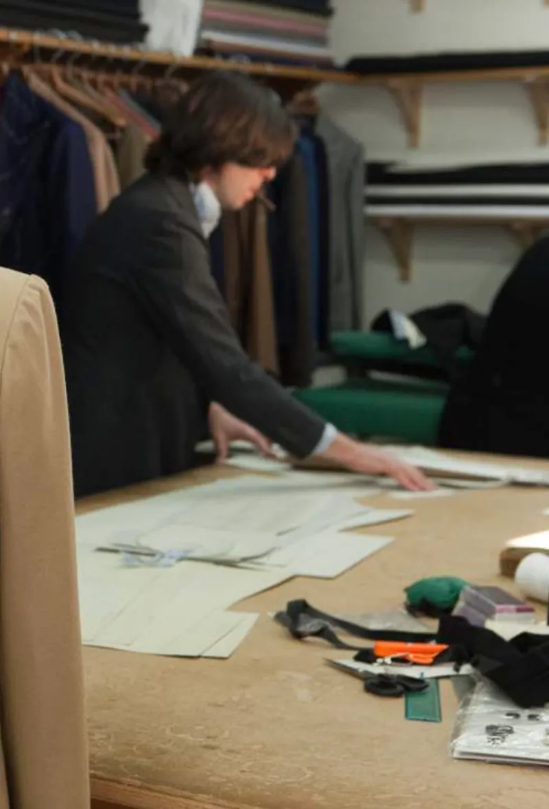 A tailor cutting a paper pattern at the workbench