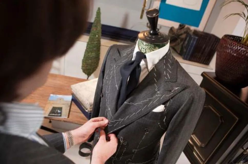 A tailor fitting a jacket on a mannequin